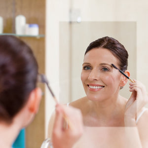 Woman in fogless mirror applying makeup